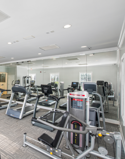 Fitness center with treadmills and other workout machines next to a mirrored wall at MAA Monthaven Park luxury apartments in Hendersonville, TN