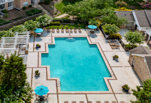 Aerial view of resort-style pool with lounge chairs, sun umbrellas with patio tables surrounded by lush greenery at MAA Monthaven Park luxury apartments in Hendersonville, TN