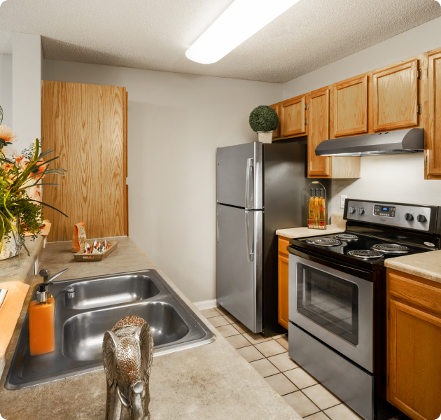 Apartment kitchen with light brown wood cabinets, stainless steel appliances and bar top counter with a double sink at MAA Murfreesboro luxury apartments in Murfreesboro, TN