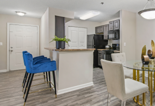 Side view of kitchen with bar top counters with barstool blue chairs next to the dining area at MAA Nashville West luxury apartments in Nashville, TN