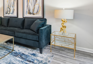 Close up view of living room with side table and lamp, black couch on area rug with wood floors at MAA Nashville West luxury apartments in Nashville, TN