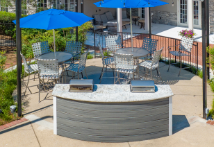 Poolside grilling station area with blue umbrellas with patio table and chairs at MAA Nashville West luxury apartments in Nashville, TN