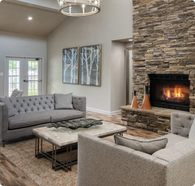 Community clubhouse with double French doors, brick fireplace and cozy sitting area with a marble coffee tables on wood floors at MAA Park luxury apartments in Hermitage, TN