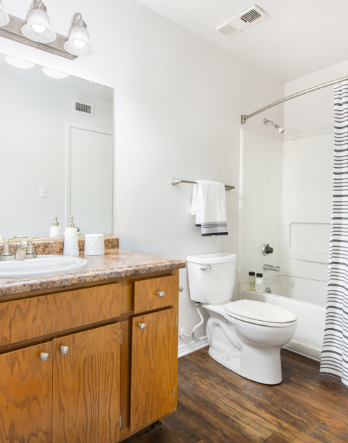 Bathroom with vanity mirror and sink with wood cabinets on wood floors at MAA Park luxury apartments in Hermitage, TN