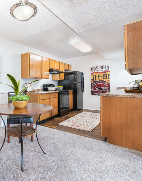 Open-style kitchen with light brown cabinets, upgraded appliances and wood floors next to a dining area at MAA Park luxury apartments in Hermitage, TN