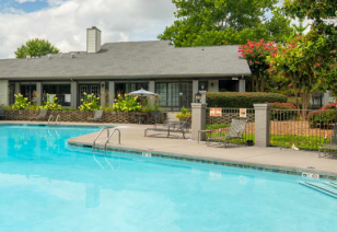 A swimming pool with lounge chairs surrounded by lush greenery next to the clubhouse at MAA Park luxury apartments in Hermitage, TN