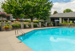 Side view of a gated pool with metal handrails and lounge chairs surrounded by lush greenery at MAA Park luxury apartments in Hermitage, TN