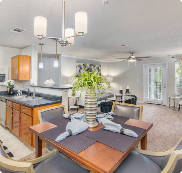 Model apartment with open space living area with a ceiling fan and French doors, next to the kitchen and dining area at MAA Sam Ridley luxury apartments in Smyrna, TN
