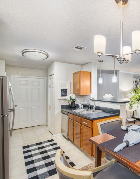 Modern kitchen with upgraded appliances, hanging light fixtures over a bar top counter with wood cabinets and tile floors next to a dining area at MAA Sam Ridley luxury apartments in Smyrna, TN