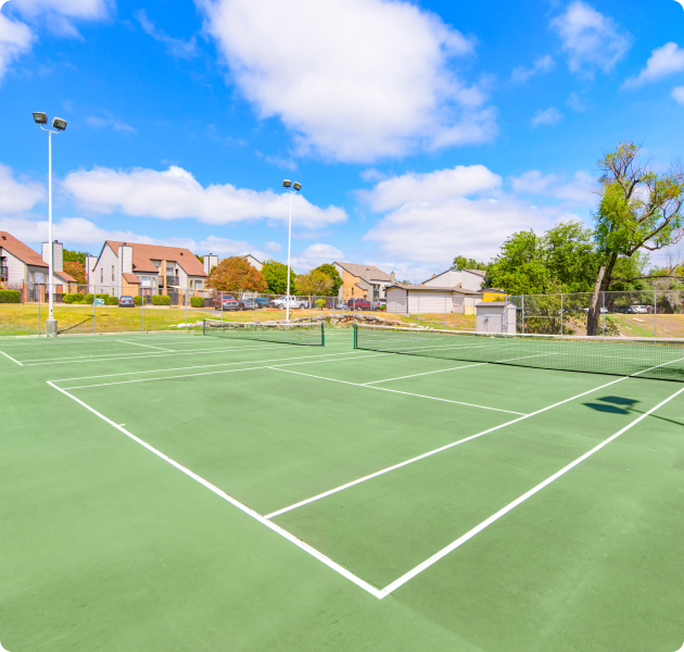 Community gated double tennis courts with light poles next to the apartment complex at MAA Balcones Woods luxury apartments in Austin, TX