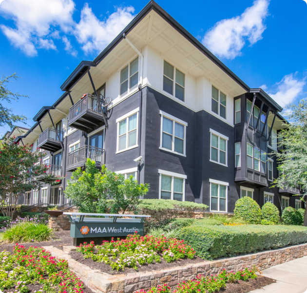Community corner view of the exterior apartment building with dark blue and white walls with large windows and balconies with signage at MAA West Austin luxury apartments in Austin, TX