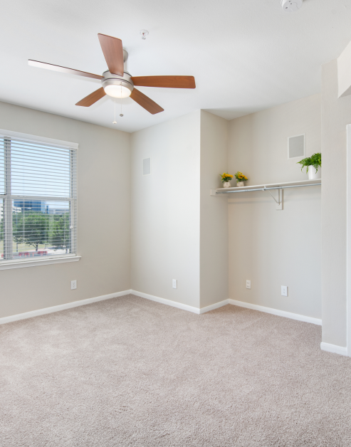 Carpeted empty bedroom with ceiling fan and shelving MAA Addison Circle luxury apartments in Addison, TX