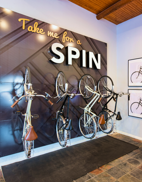 A bicycle rental station with multiple bike racks on the wall and tiled flooring at MAA Bella Casita luxury apartments in Irving, TX