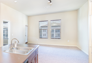 An open space living room featuring recessed ceiling lighting and large windows, next to kitchen with double sink at MAA Bella Casita luxury apartments in Irving, TX