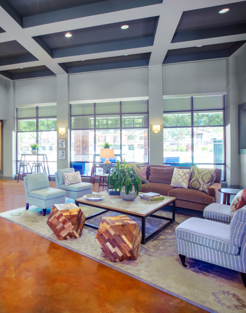 Community clubhouse with lounge seating and bar top areas with large picture windows and modern décor at MAA Copper Ridge luxury apartments in Roanoke, TX