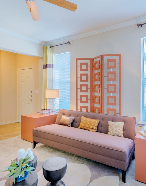 A vibrant living room with contemporary décor with side light windows, couch and coffee table on carpeted flooring at MAA Copper Ridge luxury apartments in Roanoke, TX