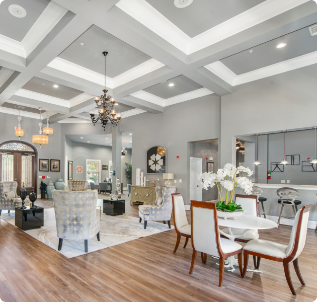 A spacious lounge with multiple sitting areas with chandeliers, a bar counter and hardwood floors at MAA Fairview luxury apartments in Fairview, TX