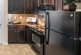 A luxurious kitchen featuring a refrigerator, gas stove, and dark wood cabinets at MAA Fairview luxury apartments in Fairview, TX