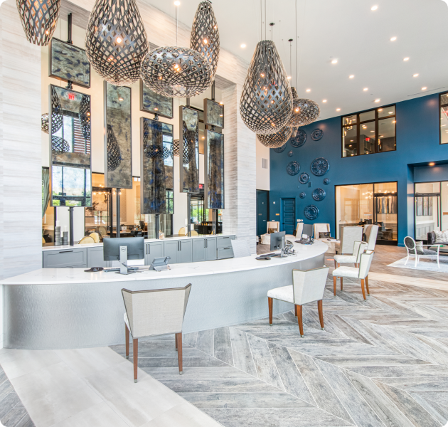 Modern chic-style leasing center with hanging light fixtures, mirror wall art and a blue accent wall at MAA Frisco Bridges luxury apartments in Frisco, TX