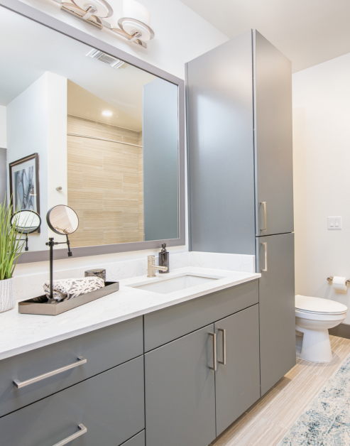 Modern-style bathroom with a single sink and large vanity mirror with gray cabinets at MAA Frisco Bridges luxury apartments in Frisco, TX