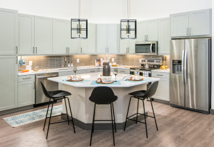 Kitchen with dining table island and chairs with stainless steel appliances and wood floors at MAA Frisco Bridges luxury apartments in Frisco, TX