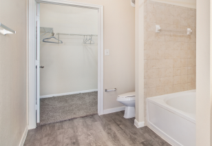 A bathroom features a large walk-in closet and a bathtub with hard flooring at MAA Hebron luxury apartments in Carrollton, TX