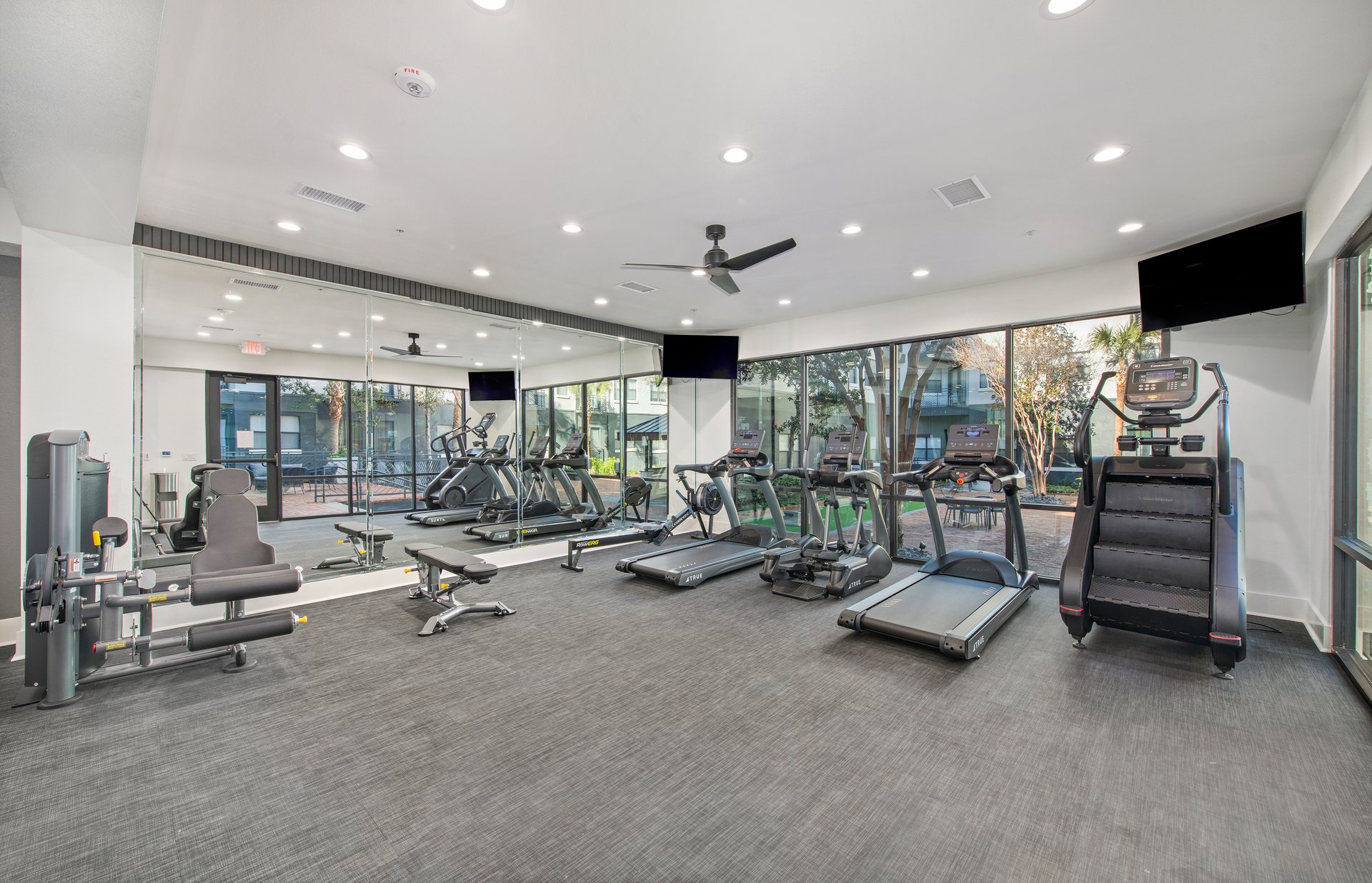 Fitness center features treadmills, a stair climber, and large picture windows at MAA Heights luxury apartments in Dallas, TX