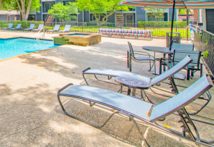 Poolside patio table with chairs and lounge chairs at MAA Highlands North luxury apartments in Dallas, TX