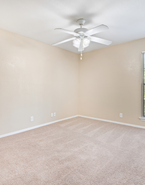 An open-space bedroom with carpeted flooring and a ceiling fan at MAA Highwood luxury apartments in Plano, TX