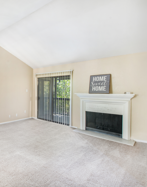 A spacious open carpeted living room featuring a fireplace and sliding glass doors at MAA Highwood luxury apartments in Plano, TX