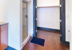 Bathroom with light brown wood flooring next to shower with glass door at MAA Las Colinas luxury apartments in Irving, TX