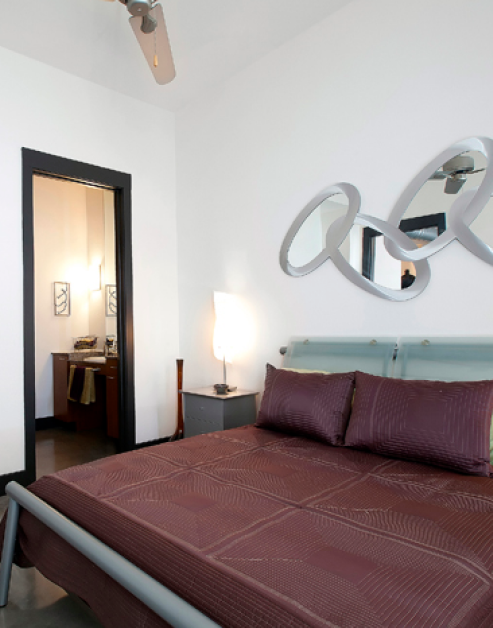 Bedroom with stylish modern wall décor above bed and ensuite bathroom at MAA Las Colinas luxury apartments in Irving, TX