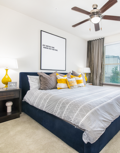 Carpeted bedroom with queen box bed and dark curtains at MAA Market Center luxury apartments in Plano, TX