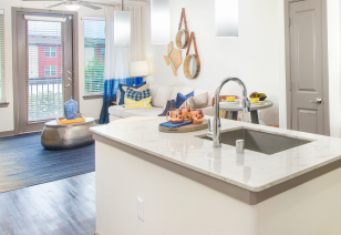 Modern kitchen with white granite island countertop with faucet sink at MAA Market Center luxury apartments in Plano, TX