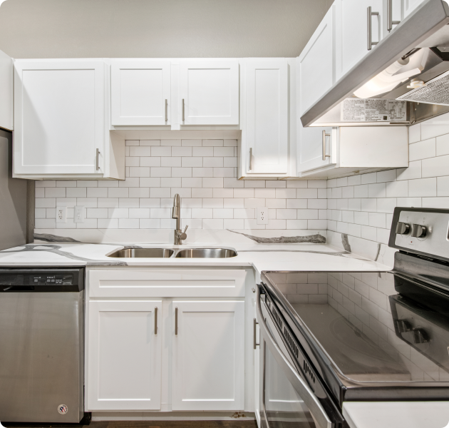 A modern apartment featuring a white kitchen equipped with appliances, stylish tile backsplash with white cabinets at MAA McKinney Ave luxury apartments in Dallas, TX