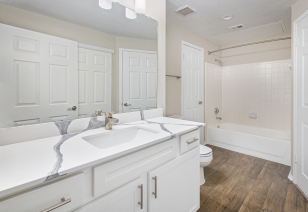 A spacious bathroom with a bathtub, large vanity mirrors and hard flooring at MAA McKinney Ave luxury apartments in Dallas, TX