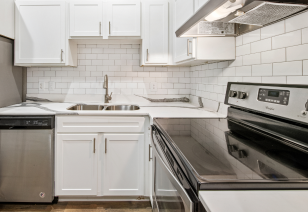 A modern kitchen with upgraded appliances including an electric stove and white cabinets at MAA McKinney Ave luxury apartments in Dallas, TX