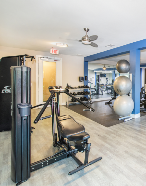 A fitness center equipped with exercise machines, free weight racks and exercise balls and ceiling fans at MAA Medical District luxury apartments in Dallas, TX