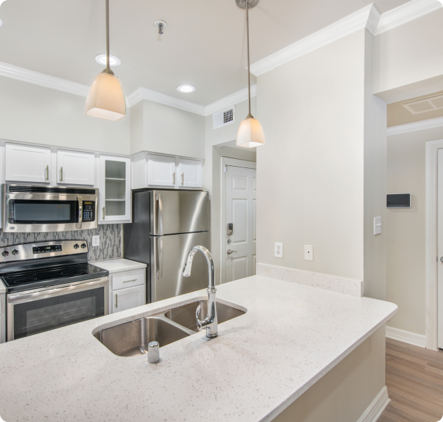 Modern kitchen interior with stainless steel appliances, white cabinets, and hanging pendant lights at MAA Meridian luxury apartments in Dallas, TX