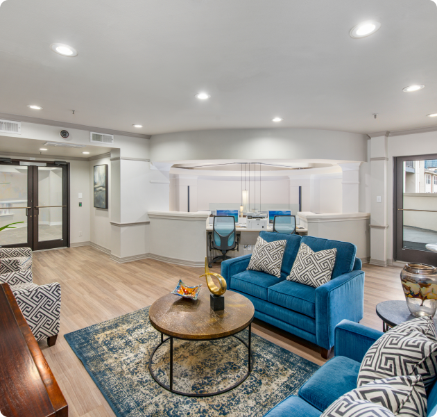 Community lounge features blue sofas, a patterned rug, a round table, complemented by a conference table in the business center at MAA Meridian luxury apartments in Dallas, TX