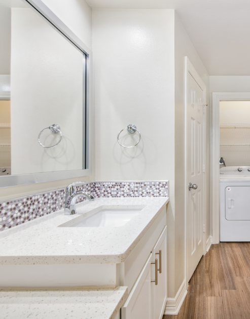 A spotless bathroom with a contemporary sink, an expansive vanity mirror, and clean white cabinets at MAA Meridian luxury apartments in Dallas, TX