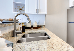 Kitchen sink with granite countertop and stainless steel faucet next to white side cabinets at MAA North Hall luxury apartments in Dallas, TX