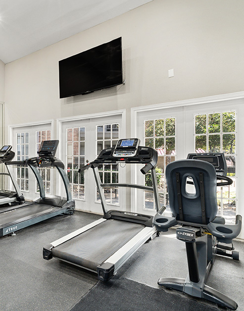 A fitness center with treadmills and weight machines next to the entrance door at MAA Remington Hills luxury apartments in Irving, TX