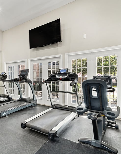 A fitness center with treadmills and weight machines next to the entrance door at MAA Remington Hills luxury apartments in Irving, TX