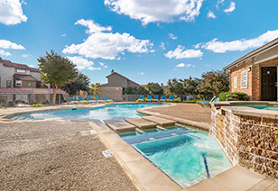 A side view of a resort-style swimming pool with lounge chairs and trees at MAA Remington Hills luxury apartments in Irving, TX
