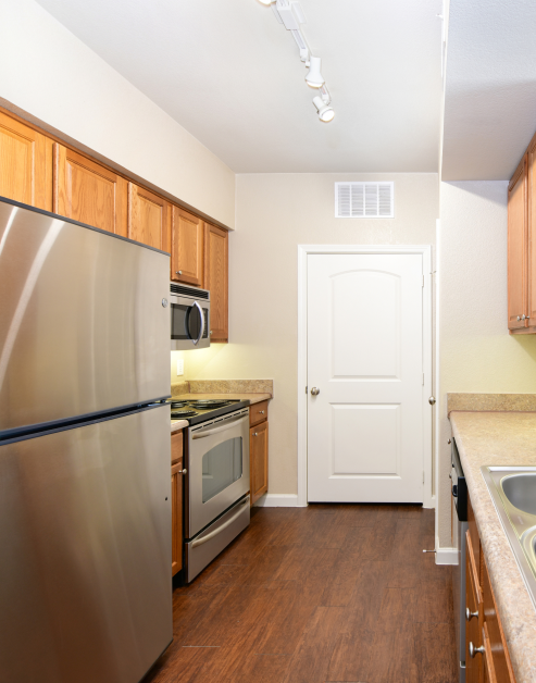 Upscale modern kitchen with stylish brown cabinets, hardwood floors and upgraded appliances at MAA Starwood luxury apartments in Frisco, TX