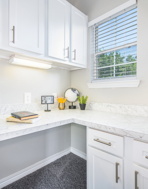A functional home office room with a desk, modern white cabinets with a window view at MAA Stonebridge Ranch luxury apartments in McKinney, TX