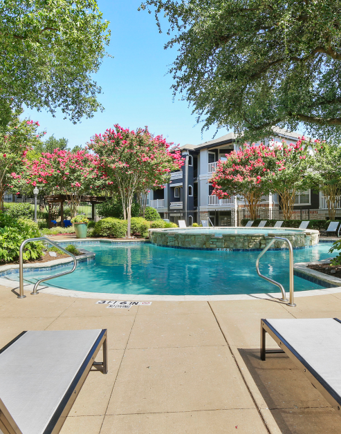 A serene pool surrounded by lush trees and bushes at MAA Stonebridge Ranch luxury apartments in McKinney, TX
