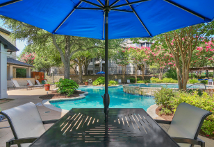 Poolside sun umbrella with table view and lush greenery at MAA Stonebridge Ranch luxury apartments in McKinney, TX