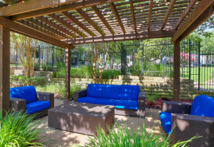 Poolside pergola with blue cushions lounge area surrounded by lush greenery at MAA Stonebridge Ranch luxury apartments in McKinney, TX